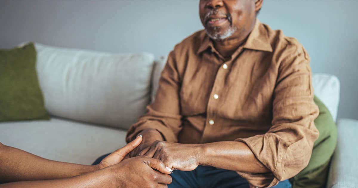 Adult daughter holding the hands of her elderly father who has early onset dementia.